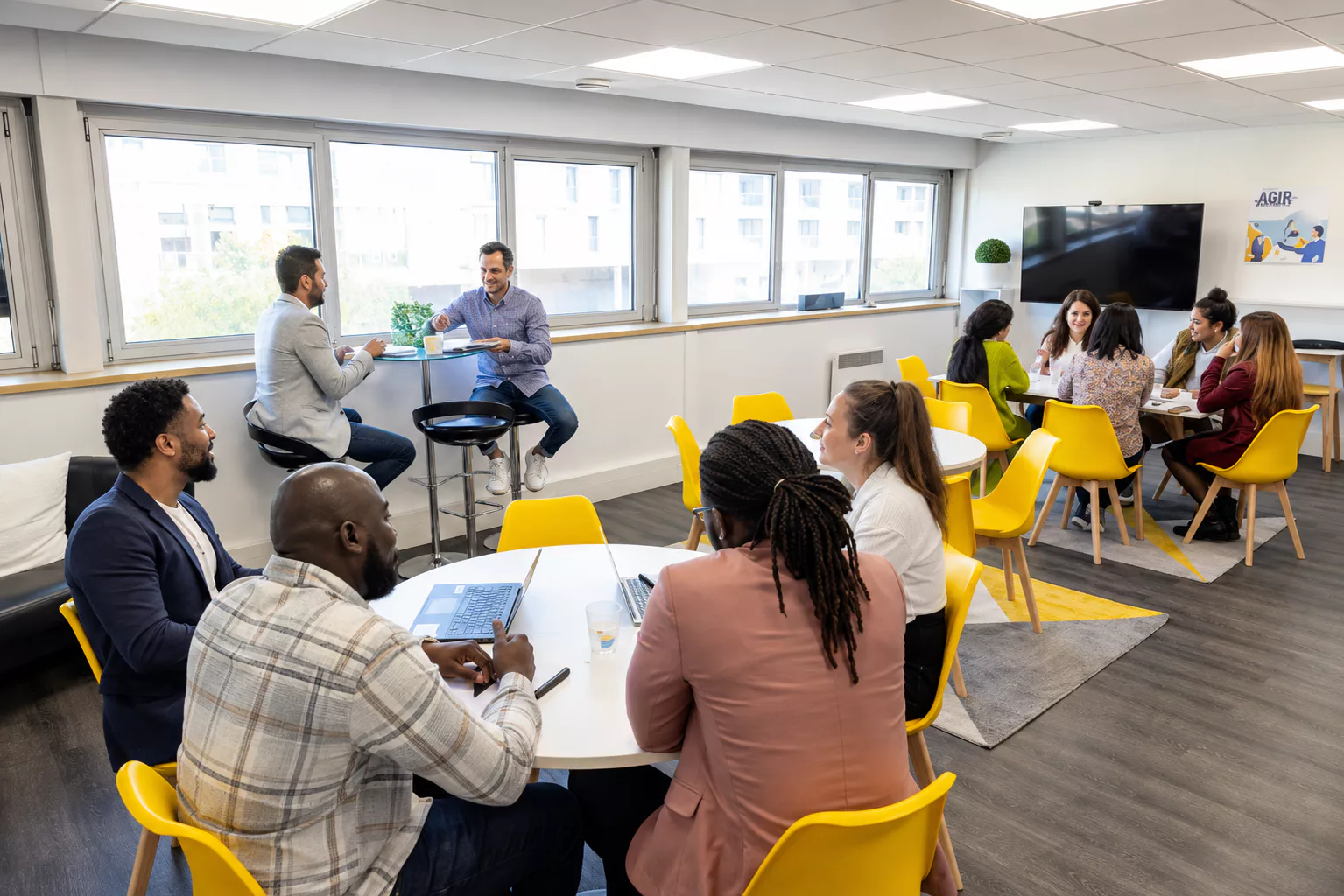 Collaborateurs OBOXIA réunis en petits groupes de travail dans l'espace atelier de l'agence